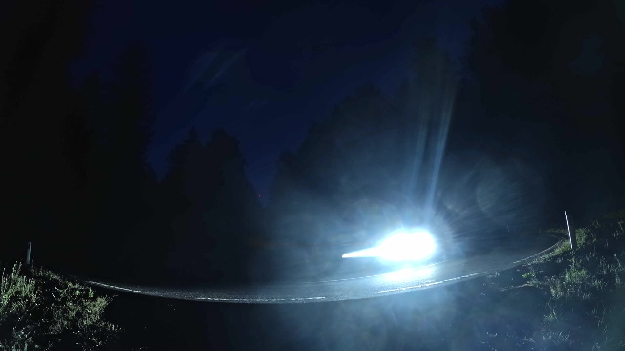 Moving cars long exposure light trails on a dark forest road at night