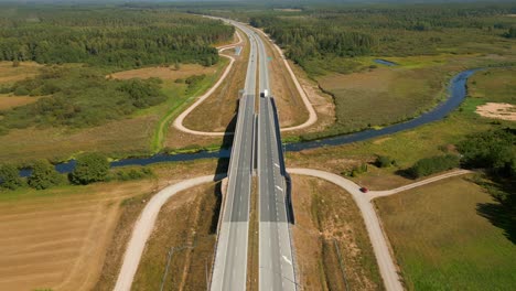 trucks driving on expressway highway through forested landscape, elk river in view, aerial view