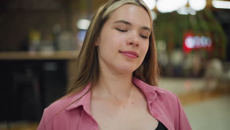 dama de vestido rosa sonriendo con la cabeza inclinada hacia atrás en una postura relajada mueve su cabeza alrededor, disfrutando de un momento de paz y satisfacción, con efecto de luz borrosa en el fondo