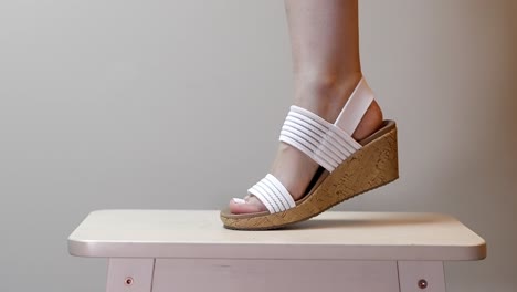 Woman-flexes-leg-with-foot-wearing-white-platform-cork-heels-twisting-side-to-side