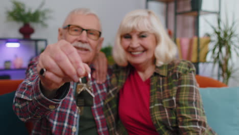 Feliz-Pareja-De-Familia-Senior-Abuelos-Hombre-Mujer-Mirando-La-Cámara-Demostrando-Las-Llaves-Del-Piso-Nuevo