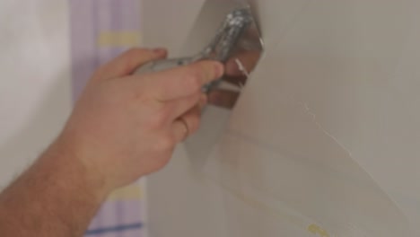 man plastering the walls with finishing putty in room with putty spatula