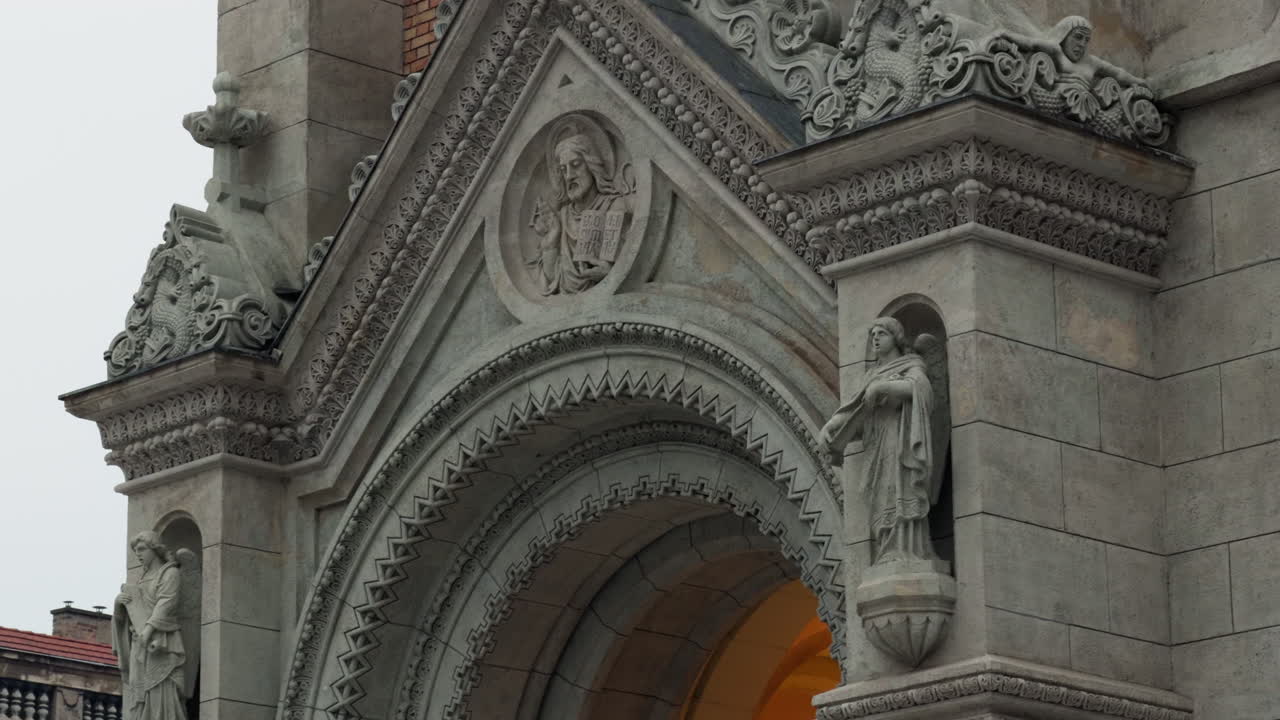 Primo piano di elaborati intagli in pietra e sculture religiose sulla chiesa parrocchiale di San Francesco d'Assisi a Budapest, che evidenzia la storica architettura cattolica, l'artigianato e i dettagli del patrimonio europeo
