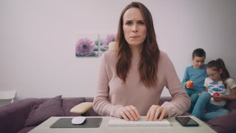 Madre-Infeliz-Trabajando-En-La-Computadora-En-Casa-Con-Niños.-Mujer-Concentrada