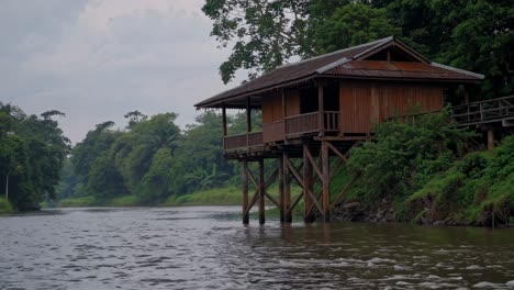 wooden cabin on a riverbank in the jungle