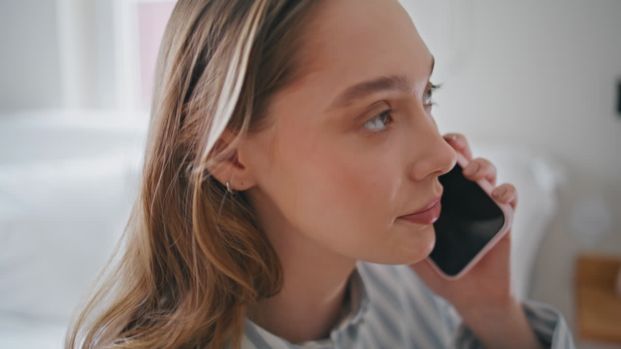 Carefree woman talking cell phone in cozy bedroom closeup. Relaxed lady calling