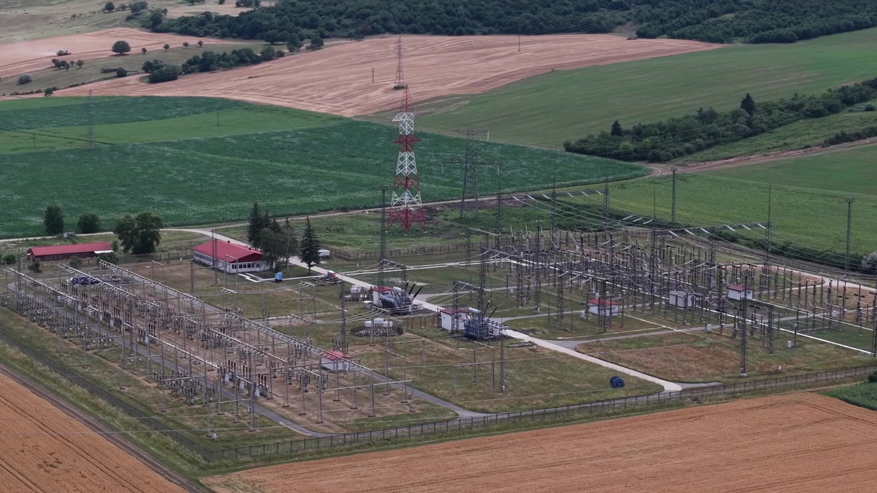 Eine Luftaufnahme eines Umspannwerks in ländlichen Feldern, das die Versorgungsinfrastruktur und die nachhaltige Energieverteilung im Netz darstellt.