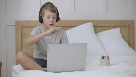 little boy is viewing cartoons or children movie by laptop and drawing lying on bed at his room