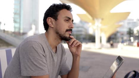 Pensive-man-with-tablet-pc-on-street