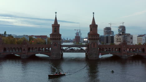 Toma-Aérea-De-Dos-Torres-Del-Puente-Oberbaum-En-Berlín,-Alemania,-Que-Revela-Una-Vista-Del-Horizonte-Sobre-El-Río-Spree