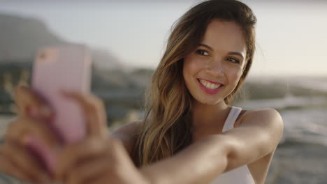 portrait of attractive hispanic woman at beach taking selfie