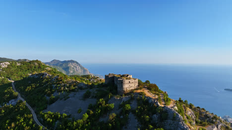 Drone-shot-circling-the-Fort-Kosmac-castle,-sunny-evening-in-Budva,-Montenegro