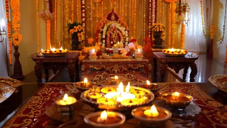 a hindu altar with candles, diyas, and flowers