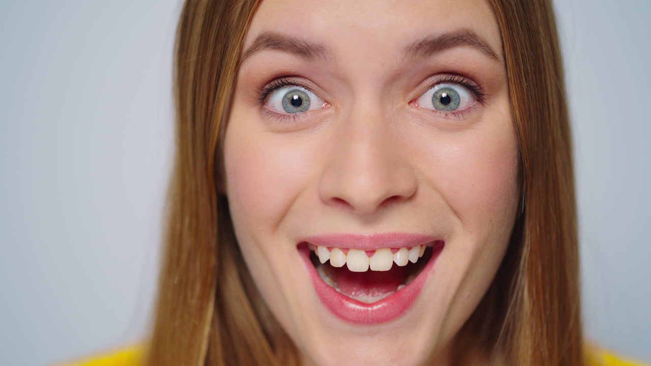Portrait of surprised beautiful woman posing on grey background in studio.