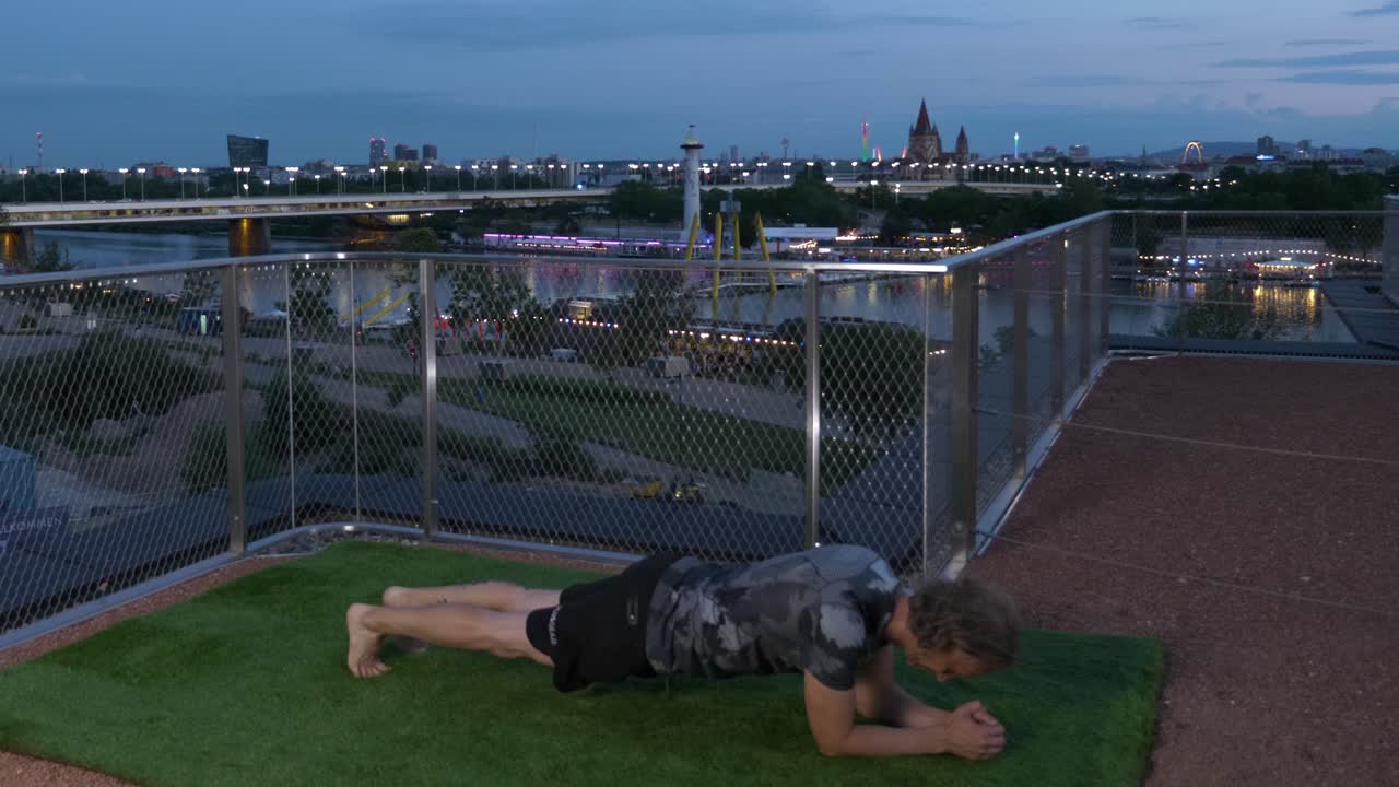 오스트리아 비엔나의 다뉴브 강을 배경으로 저녁에 테라스에서 보드를 하고 있는 남자, 4k 타임  ⁇ 스