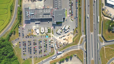 aerial view of the logistics park with warehouse, loading hub and many semi trucks with cargo trailers standing at the ramps for load unload goods at sunset