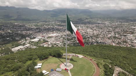 slow aerial view of the waving mexico independence declaration flag above iguala