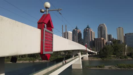 City-bridge-with-pedestrians-over-a-river-with-skyscrapers-on-a-sunny-day-Calgary-Alberta-Canada