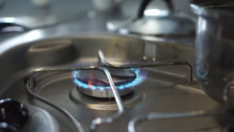 close up - lighting up gas stove burner fire and a pot of water in kitchen of motorhome