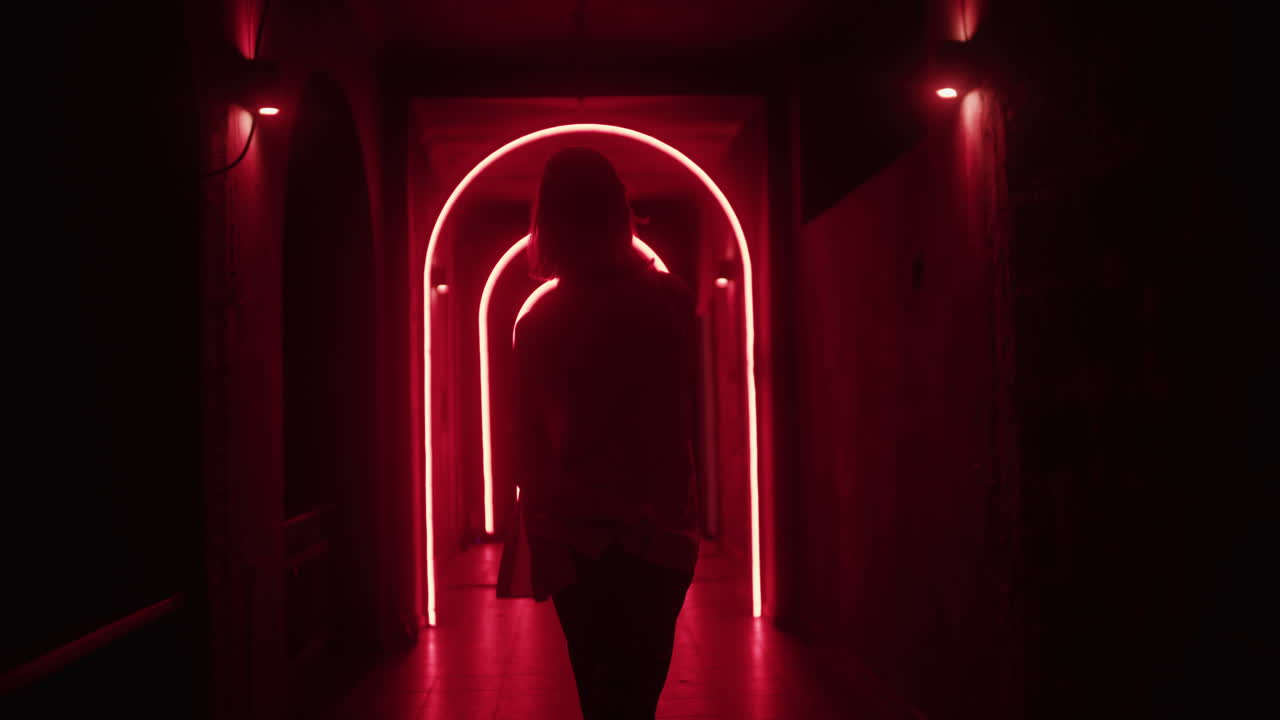 Donna che cammina attraverso un tunnel illuminato al neon