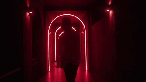 woman walking through a neon-lit tunnel