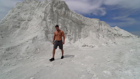 strong man with athletic body comes to barbell on beautiful white mountain. slow motion. strength and endurance training for wrestlers.
