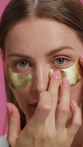 mujer aplicando parches de oro en los ojos