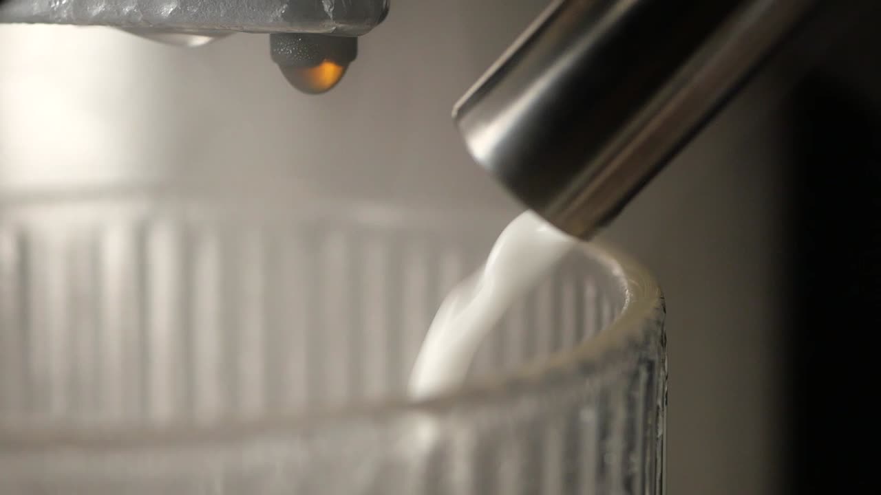 Close-up of coffee machine pouring milk into a glass