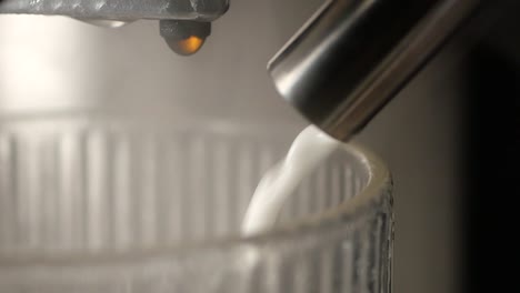 close-up of coffee machine pouring milk into a glass