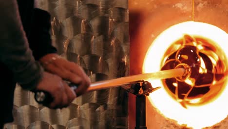 glassblower heating a glass in furnace