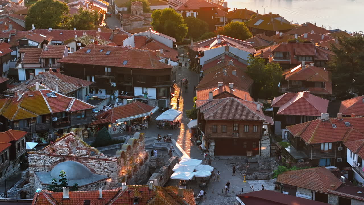 Aerial drone view of people moving through the old town Nessebar, Bulgaria at sunset