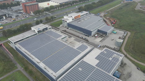 aerial of industrial rooftop filled with solar panels near busy highway