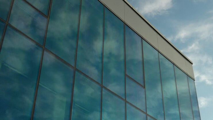 Glass building facade reflecting blue sky and clouds