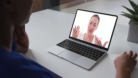 sección media de una mujer afroamericana haciendo una videollamada en una computadora portátil con una colega en la oficina
