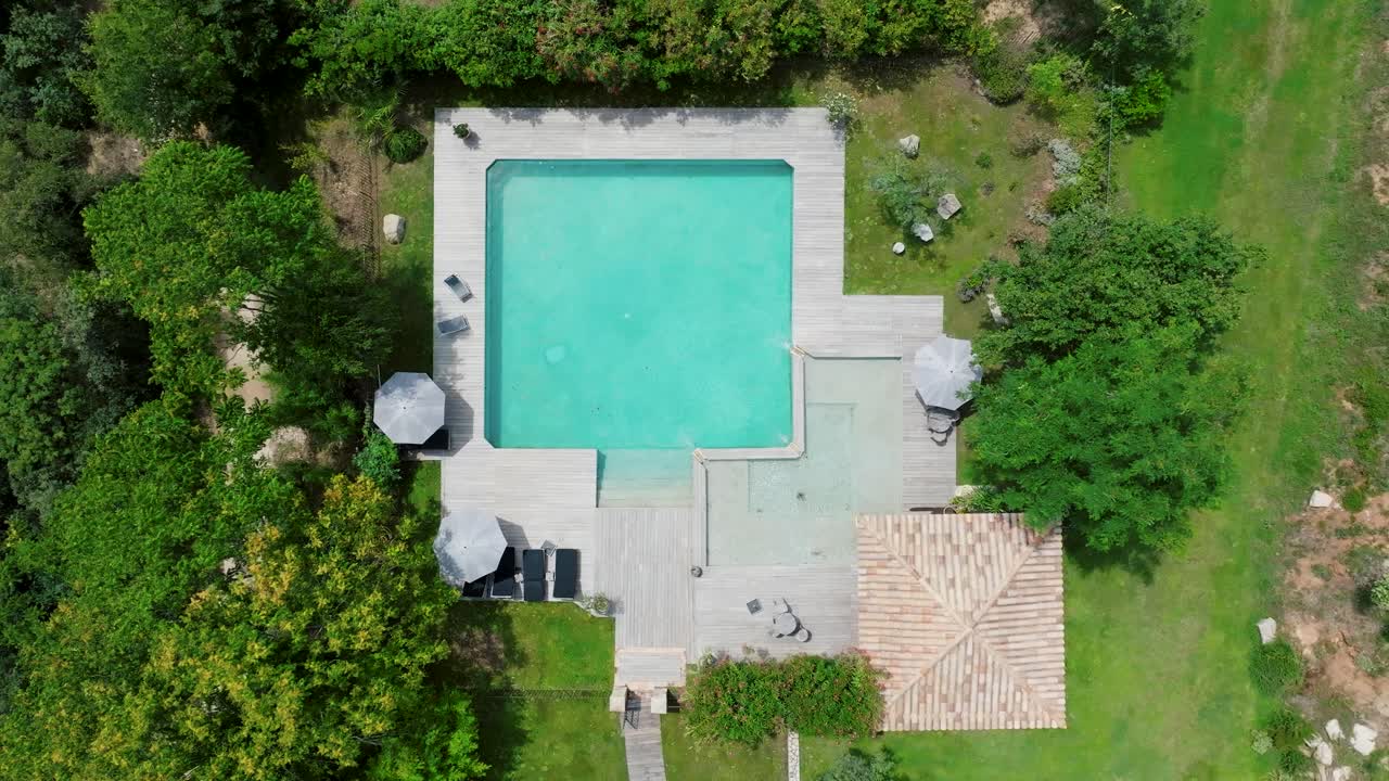 Luftfoto fra oven af en udendørs swimmingpool ved Domaine Sainte Colombe, Frankrig, der fremhæver dens design og omgivelser, ideel til koncepter som luksus, afslapning og eksklusiv fritid