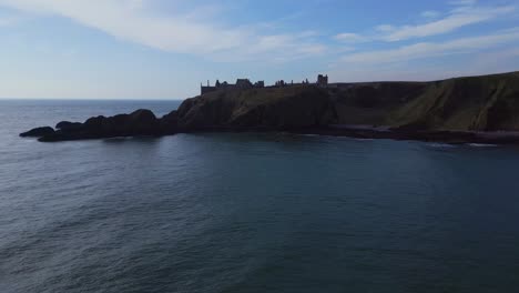 Gracefully-soaring-through-towering-cliffs,-overlooking-the-vast-expanse-of-the-ocean-towards-the-magnificent-Dunnottar-Castle-in-Scotland