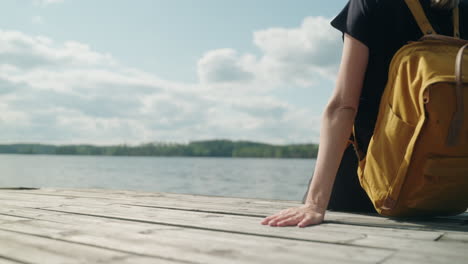 women-sits-on-a-pier-on-a-sunny-day,-static,-wide