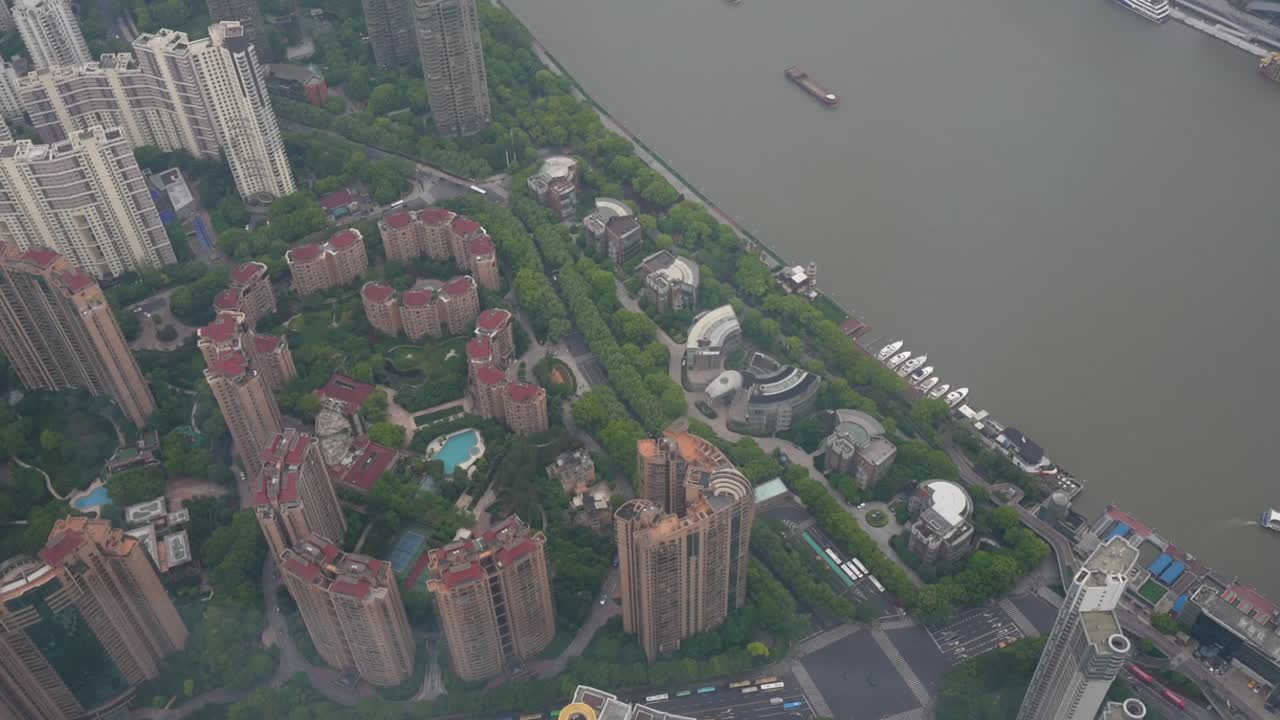 Top down perspective of mixed high-rise blocks and green pockets beside the Huangpu River from the observation deck. Shanghai, China
