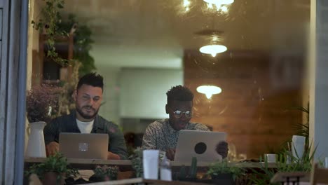 Freelancers-talking-and-using-laptops-in-cafe