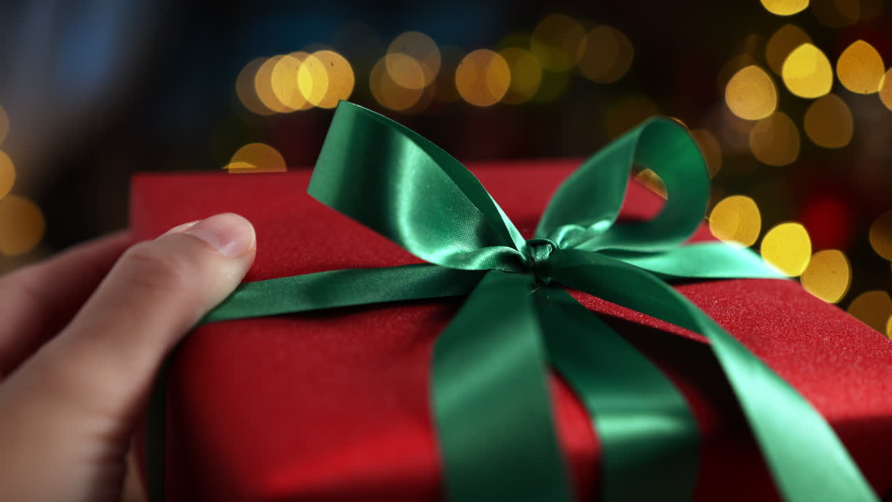 Hand Untying A Green Satin Ribbon From A Gift Wrapped In Red Wrapping Paper - Slow Motion
