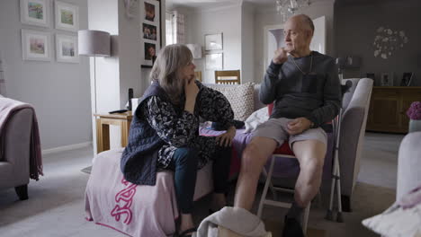 an elderly man and woman having a conversation in their living room