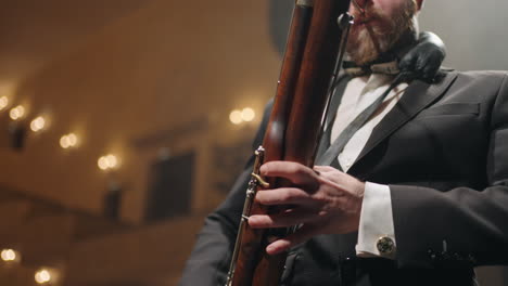 adult man with bassoon is playing music on scene of old music hall classic music concert in opera house