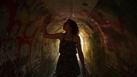 caucasian girl in a green floral dress walks in a tunnel at sunset, medium shot