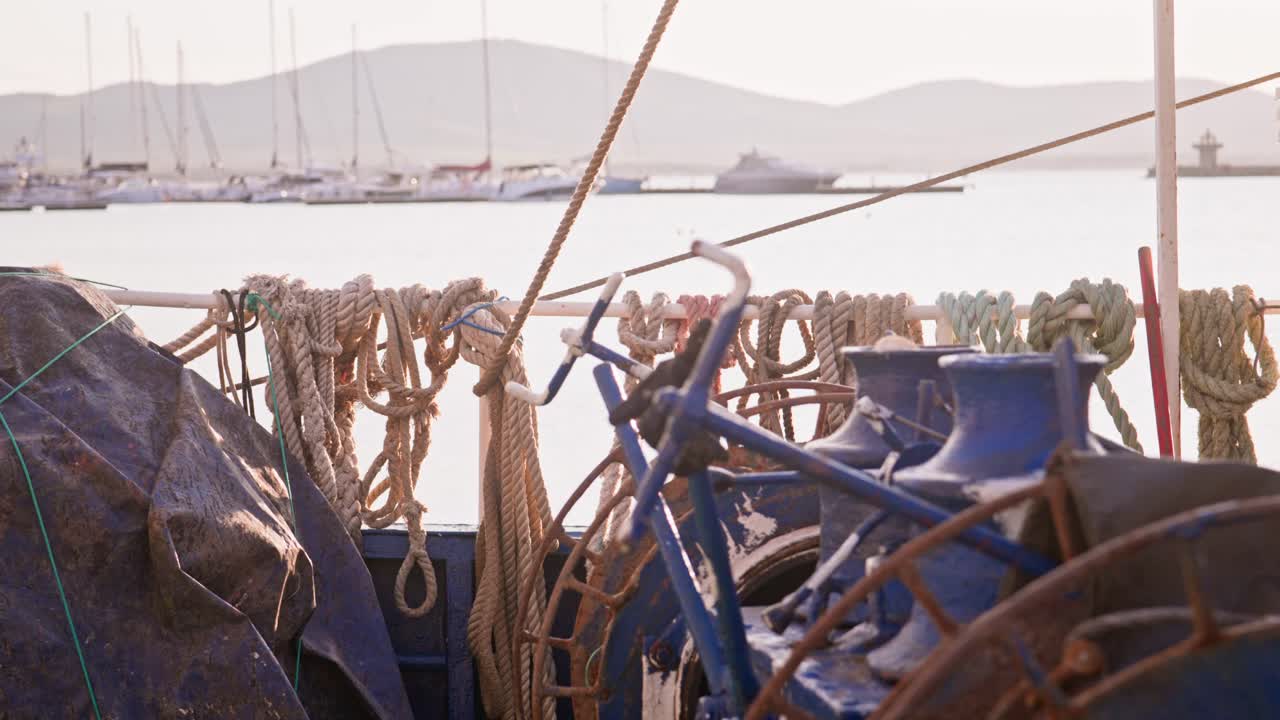 Warm sunlight over sea port and fishing trawler boat deck equipment