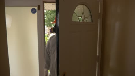 worker in white hazmat suit enters house which contains asbestos