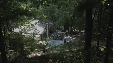 pov shot se mueve lentamente a través de los árboles del bosque hacia la casa de campo sombreada