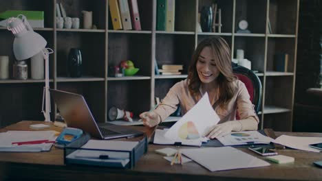 smiling businesswoman reading documents with good statistics graph at desk