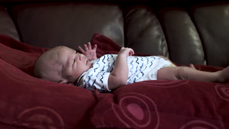 tranquilo y adorable bebé recién nacido mirando a la madre mientras se acuesta en el sofá de almohadas