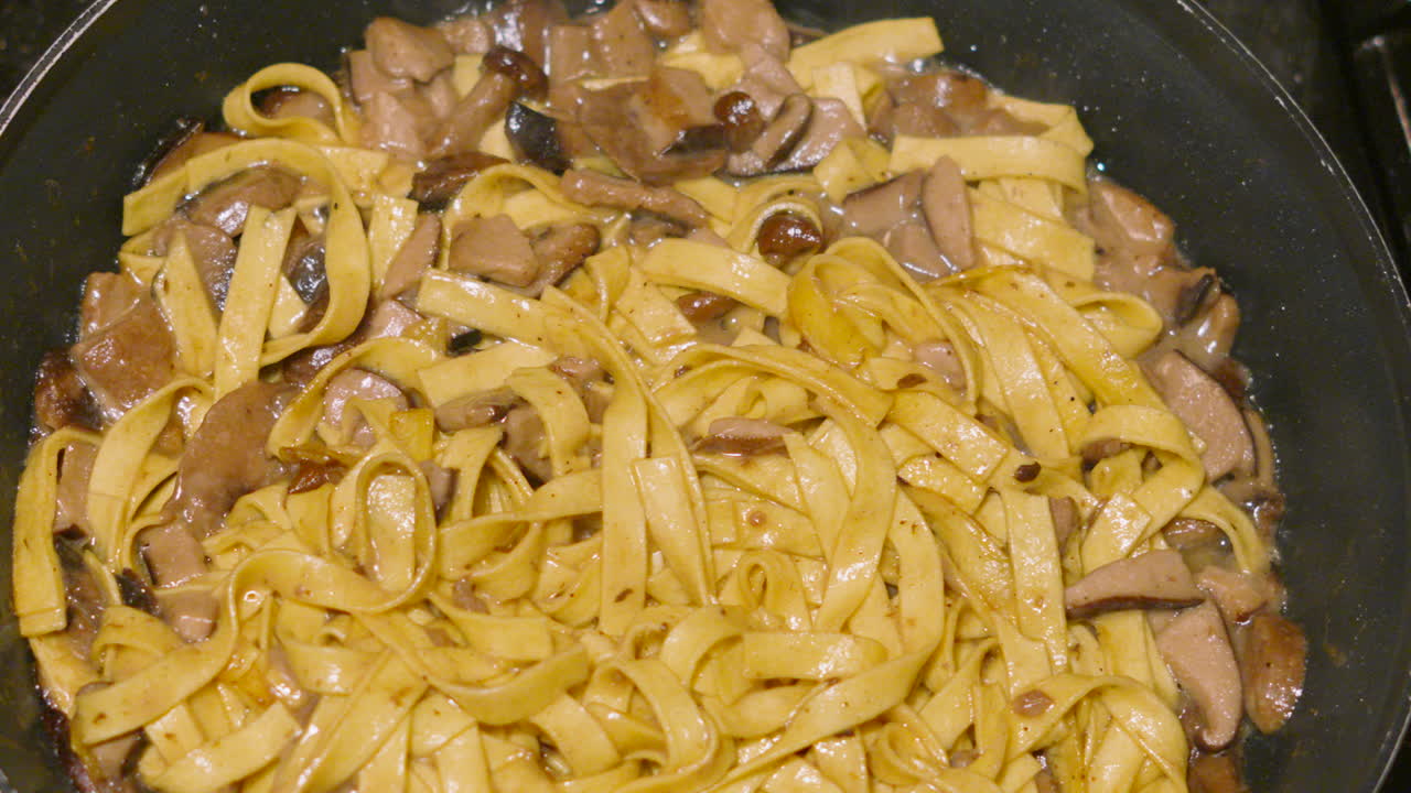 Italian Cuisine Fresh Mushroom Tagliatelle Being Cooked Gently in Hot Pan with Various Fungi Including Champignon, Shitake, Nameko. Home Cooked Cream Sauce Based Pasta Dish.