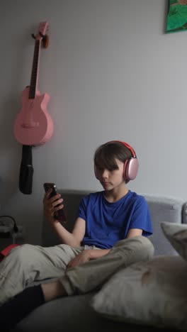 teenager listening to music on smartphone on couch